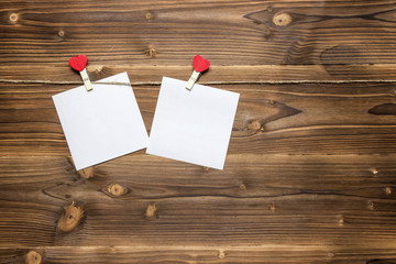 Two white sheets of paper hanging on clothespins with small hearts, copy space.