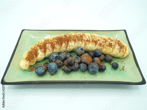 Cuadros en Lienzo Postre de plátano con arándanos y cacao puro en polvo.