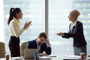 mad middle aged businesswoman have dispute with young asian employee blaming for mistake in document