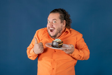 Funny fat man in orange shirt with a piece of chocolate cake on a plate