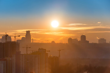 Poster - Panoramic view of sunset in the city with silhouette of buildings and industrial cranes