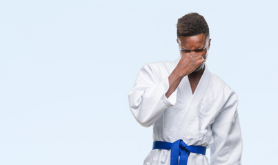 Wall Mural - Young african american man over isolated background wearing kimono smelling something stinky and disgusting, intolerable smell, holding breath with fingers on nose. Bad smells concept.