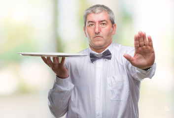 Canvas Print - Handsome senior waiter man holding silver tray over isolated background with open hand doing stop sign with serious and confident expression, defense gesture