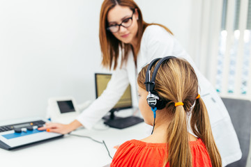 Young girl at medical examination or hearing aid checkup in otolaryngologist's office