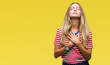 Young beautiful blonde woman over isolated background smiling with hands on chest with closed eyes and grateful gesture on face. Health concept.