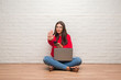 © Krakenimages.com - Young brunette woman sitting on the floor using laptop and smartphone with open hand doing stop sign with serious and confident expression, defense gesture