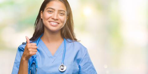 Young arab doctor surgeon woman over isolated background doing happy thumbs up gesture with hand. Approving expression looking at the camera with showing success.