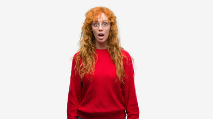 Sticker - Young redhead woman wearing red sweater afraid and shocked with surprise expression, fear and excited face.