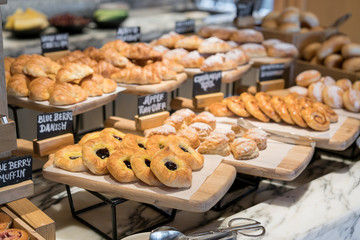 Breakfast lines of different flavor danishs, buns and muffins in wooden trays at the hotel restaurant