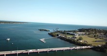 Aerial Drone Shot Of Cars Driving On A Bridge. Boats Sailing At The Sea, On A Warm And Sunny Day, At Bribie Island, In Queensland, Australia