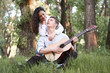 © soleg - young couple sitting in the forest and playing guitar, summer nature, bright sunlight, shadows and green leaves, romantic feelings