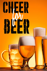 Wall Mural - arranged mugs of cold beer with froth on orange background with 