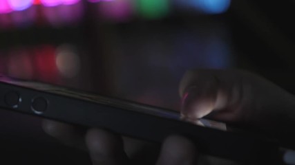 Close-up image of a child's hands using a smartphone at night on a city shopping street, search or social network concept, a hipster man typing a sms message to his friends