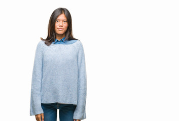 Canvas Print - Young asian woman wearing winter sweater over isolated background with serious expression on face. Simple and natural looking at the camera.