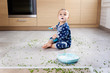 © Lisa Tichané - Messy toddler sitting on kitchen floor with peas and yogurt