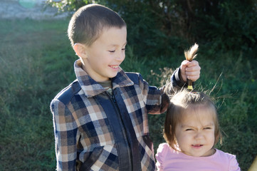 Wall Mural - Children having fun. Boy and little girl portrait. Happy smiling children outdoors at sunny day. Friendship siblings. Brother joking on little sister