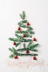 Wall Mural - top view of green pine branch decorated as festive christmas tree with glitters on white background