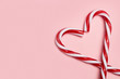 Bastones de caramelo formando un corazón sobre un fondo rosa liso y aislado. Vista superior y de cerca. Copy space