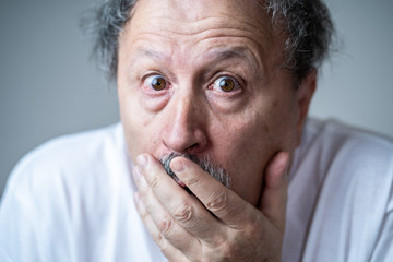 Close up of scared and shocked senior man gesturing in fear with hands and face