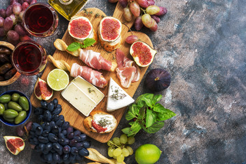 Wall Mural - A variety of appetizer, prosciutto,grapes, wine, cheese with mold, figs, olives on a rustic background. Mediterranean snack.Top view,flat lay,copy space.