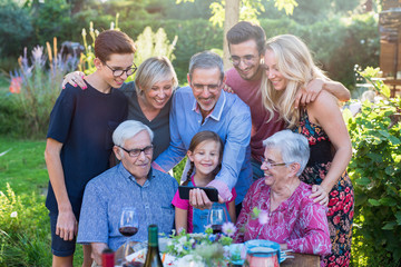  During a bbq, the family have fun sharing a video on a phone