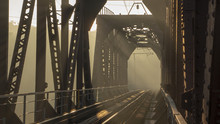 A Railway Bridge In The Morning Fog Or Smoke Through Which The Rays Of The Sun Shine