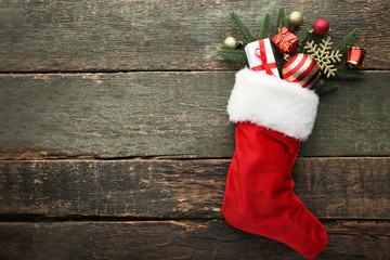 Red stocking with fir-tree branches and christmas decorations on wooden table