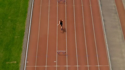 female athletic jumping over hurdle on sports track 4k