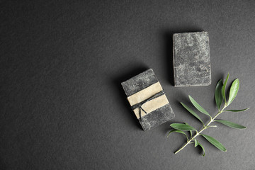 Wall Mural - Handmade soap bars with olive twig and space for text on black background, top view