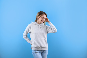 Wall Mural - Portrait of woman in hoodie sweater on color background. Space for design