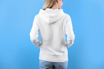 Wall Mural - Woman in hoodie sweater on color background. Space for design