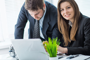 Young businessman discussing something with his colleague, and using a digital laptop together