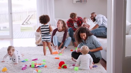 Wall Mural - Friends with toddlers playing and holding cup of cofffee