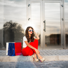 Wall Mural - Young woman with shopping bags resting near shop