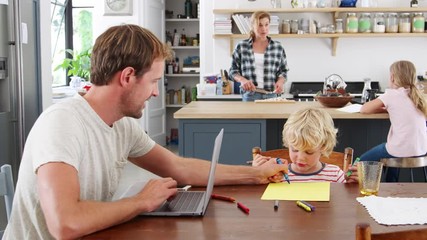 Wall Mural - Dad and son at kitchen table, mum and daughter in background