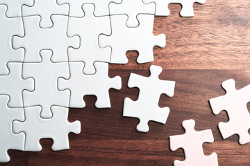 Aufkleber - Assembling jigsaw puzzle pieces. Abstract background.Unfinished white jigsaw puzzle pieces on wood table.