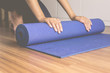© gballgiggs - Woman hand rolling or folding blue yoga mat after a workout,Exercise equipment.Healthy fitness and sport concept