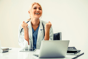 Happy successful woman doctor feels delightful in hospital or healthcare institute while working on medical report at office table. Success concept.