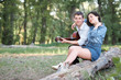 © soleg - young couple sitting on a log in the forest and playing guitar, summer nature, romantic feelings