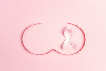 Pink ribbon with breast shape symbol on pink background.  Breast cancer awareness symbol. O