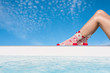 Women's feet in Christmas socks near the pool on the blue sky background. Winter concept.