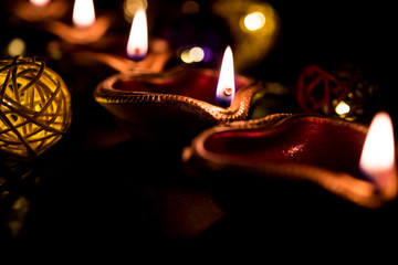 Beautiful diwali diyas at night with flowers, lighting series and gifts, moody background