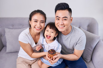 Wall Mural - Lively family eating cupcakes in the living room at home