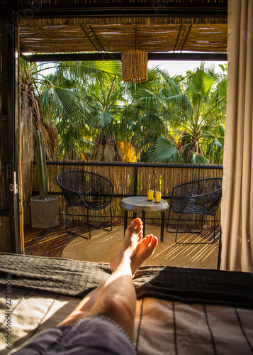 Fotografie, Obraz Resort balcony in trees with feet and beer