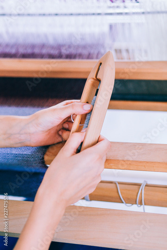 Fotografie, Obraz Female hands holding a needle for weaving against the background of a loom, lila