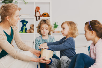 Canvas Print - Senior teacher and cute kids during music lesson in preschool