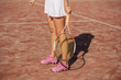 Portrait of female legs with tennis racket on red dross court, close up summer outdoor shot