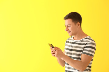 Wall Mural - young man with mobile phone on color background