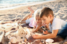 Cute Little Children Looking At Sea Shells Through Magnifying Glass On Beach
