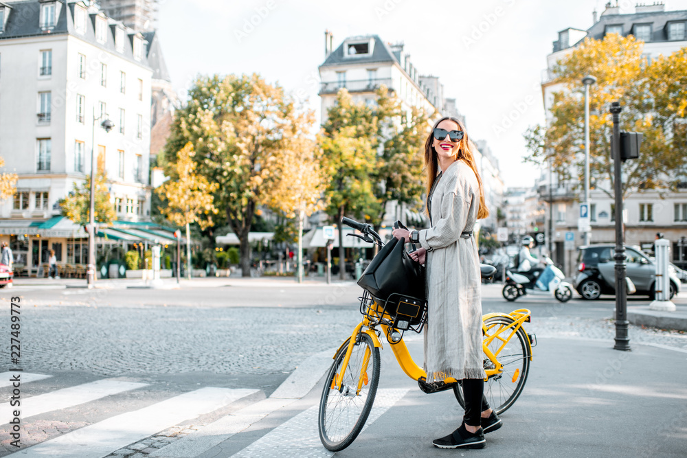 Portrait of a young stylish woman with yellow bicycle on the street in Paris - obrazy, fototapety, plakaty 